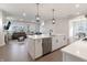 Kitchen island with quartz countertop, sink, and view to an open living area with fireplace at 15755 Scher Dr, Westfield, IN 46074