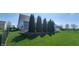 Backyard featuring a green lawn, a black chain-link fence, privacy trees, and well-maintained landscaping at 1630 Valdarno Dr, Greenwood, IN 46143