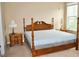 Spacious bedroom with a wooden four-poster bed, neutral walls, and a bright window providing natural light at 1630 Valdarno Dr, Greenwood, IN 46143