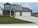Two-story home boasts a two-car garage, gray brick accents, covered porch, and manicured front yard at 240 Ames Dr, Whiteland, IN 46184