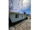 This exterior side shot shows the home's light green siding and features a pathway to the back entrance at 2627 Chase St, Anderson, IN 46016