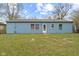 A quaint backyard with grass, a door, and windows on the light blue painted home at 3407 Allison Ave, Indianapolis, IN 46224