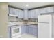 Efficient kitchen with light blue cabinets, white appliances, and neutral countertop at 3407 Allison Ave, Indianapolis, IN 46224