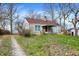 Cozy single-story home boasting a stone facade, a red roof, and a spacious front yard with mature trees in spring at 4906 S State Ave, Indianapolis, IN 46227