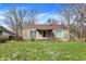 Charming stone ranch-style home featuring a cozy front porch, manicured lawn, and mature trees in a quiet neighborhood at 4906 S State Ave, Indianapolis, IN 46227