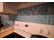 A close up of the electric stovetop, nestled into a light blue tile backsplash at 5707 W Mills Rd, Indianapolis, IN 46221