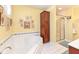 Bathroom with a garden tub, framed flower prints, and a wood cabinet at 5718 E Pleasant Run Parkway North Dr, Indianapolis, IN 46219