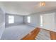 Living room features plush gray carpeting, soft gray walls, hardwood flooring, and large windows at 5989 Ashmore Ln, Carmel, IN 46033