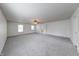 Large living room featuring plush carpeting, a ceiling fan, and abundant natural light from large windows at 5989 Ashmore Ln, Carmel, IN 46033