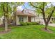 Charming home with well-manicured lawn and beautiful tree features a stone chimney and vibrant red door at 6404 Bayside Ct, Indianapolis, IN 46250