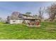 Grassy backyard featuring a fire pit and seating, surrounded by the home's exterior and lush greenery at 6413 N Wheeling Ave, Muncie, IN 47304