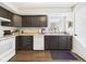 Traditional kitchen featuring dark cabinetry, white appliances, and a window over the sink at 6413 N Wheeling Ave, Muncie, IN 47304