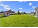 Expansive backyard featuring a large lawn, a storage shed, and mature trees under a bright blue, partly cloudy sky at 6524 Turf Way, Anderson, IN 46013