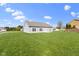 Spacious, green yard showcasing the home's exterior and surrounding neighborhood under a partly cloudy sky at 6524 Turf Way, Anderson, IN 46013