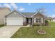 Charming single-story home with stone accents, a well-manicured lawn, and an attached two-car garage at 7951 Busby Bend Dr, Noblesville, IN 46062