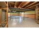 Unfinished basement with exposed ceiling, support beams, tiled and cement floor, half painted walls, and wooden shelves at 12404 Rose Haven Dr, Indianapolis, IN 46235