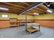 Unfinished basement with exposed ceiling, support beams, cement floor, half painted walls, and wooden shelves at 12404 Rose Haven Dr, Indianapolis, IN 46235
