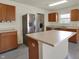 Modern kitchen features stainless steel refrigerator, island, and views into the laundry room at 12404 Rose Haven Dr, Indianapolis, IN 46235