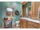 Bathroom with light-green walls, wooden cabinets, decorative wreath, vanity, and framed mirror at 1325 Fordice Rd, Lebanon, IN 46052