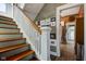 Staircase leading to the upper level with hardwood steps, white railings, and a view into the kitchen at 1325 Fordice Rd, Lebanon, IN 46052