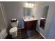 Well-lit bathroom featuring a dark wood vanity, decorative mirror, and classic white toilet at 1404 Alonzo Pl, Indianapolis, IN 46217