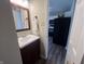 Bathroom features white sink, dark vanity, wood-look floor, wall mirror, and a view into the kitchen at 1404 Alonzo Pl, Indianapolis, IN 46217