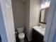 Bathroom features white toilet, dark vanity, wood-look floor and a framed mirror above the sink at 1404 Alonzo Pl, Indianapolis, IN 46217