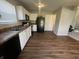 Well-lit kitchen with black appliances, white cabinetry, wood-look floors, and an adjacent door to another room at 1404 Alonzo Pl, Indianapolis, IN 46217