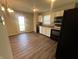 Kitchen features white cabinets, dark appliances, laminate countertops, wood-look floors, and an adjacent door to outside at 1404 Alonzo Pl, Indianapolis, IN 46217