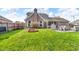 Landscaped backyard with green grass, a garden bed, and an enclosed sunroom extending from the brick home at 1598 Thornburg Ln, Franklin, IN 46131