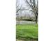 A tennis court surrounded by trees and a grassy lawn offers a place for recreation at 1813 Birch Dr, Plainfield, IN 46168