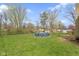 Large grassy backyard with trees, a chain link fence, and a round above-ground pool covered in blue at 2210 Douglas Rd, Indianapolis, IN 46220
