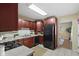 Efficient kitchen setup with cherry cabinets, neutral counters, and black appliances and easy access to other living spaces at 2210 Douglas Rd, Indianapolis, IN 46220