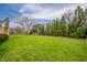 Expansive back yard featuring vibrant green grass and mature trees, creating a serene outdoor space at 2511 Ritter Dr, Anderson, IN 46012