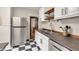 Charming kitchen with stainless steel appliances, black and white tile flooring, and wooden floating shelves at 2737 Napoleon St, Indianapolis, IN 46203