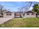 Charming single-story home featuring a gray brick exterior, a neatly landscaped front yard, and a bright turquoise front door at 322 S Boehning St, Indianapolis, IN 46219