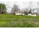 Expansive front lawn featuring the white house, sheds, and mature trees in a residential area at 359 N Whitcomb Ave, Indianapolis, IN 46224