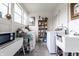 Well-lit laundry room with washer, dryer, utility sink, storage shelves, and white-washed decor at 359 N Whitcomb Ave, Indianapolis, IN 46224