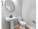 Half bath features a pedestal sink, toilet, and round mirror in a modern, minimalist design at 401 Iowa St, Indianapolis, IN 46225