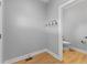 Entryway with coat hooks and a view into a half bath, with light gray walls and wood flooring at 401 Iowa St, Indianapolis, IN 46225