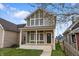 Charming two-story home with a welcoming front porch and landscaped lawn on a partly cloudy day at 401 Iowa St, Indianapolis, IN 46225
