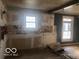 Interior shot of living room area with exposed drywall, unpainted walls, and original hardwood flooring at 5657 E Fall Creek Pkwy N Dr, Indianapolis, IN 46226