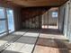 Large living room under renovation with exposed framing, plywood flooring and adjacent doorway to sunroom at 5657 E Fall Creek Pkwy N Dr, Indianapolis, IN 46226