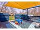 Back patio featuring seating and a shade cover adjacent to a fenced area and well manicured garden at 6170 Shelbyville Rd, Indianapolis, IN 46237