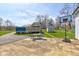 Spacious backyard featuring a patio with dining, basketball court, storage shed and playset under a sunny blue sky at 6170 Shelbyville Rd, Indianapolis, IN 46237