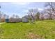 Open backyard with shed and playset under a bright blue sky with scattered clouds providing ample space for outdoor activities at 6170 Shelbyville Rd, Indianapolis, IN 46237