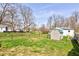 Large grassy backyard features mature trees and a storage shed, perfect for outdoor activities at 6170 Shelbyville Rd, Indianapolis, IN 46237