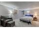 A furnished bedroom features a queen bed, sitting chair with ottoman and soft neutral decor at 6170 Shelbyville Rd, Indianapolis, IN 46237