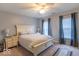 Well-lit bedroom features a queen-sized bed, neutral walls, and blue curtains on the windows at 6272 Turnbridge Dr, Avon, IN 46123