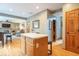 View of the kitchen island with wood cabinets and hardwood floors that opens into the living room with a fireplace at 6272 Turnbridge Dr, Avon, IN 46123
